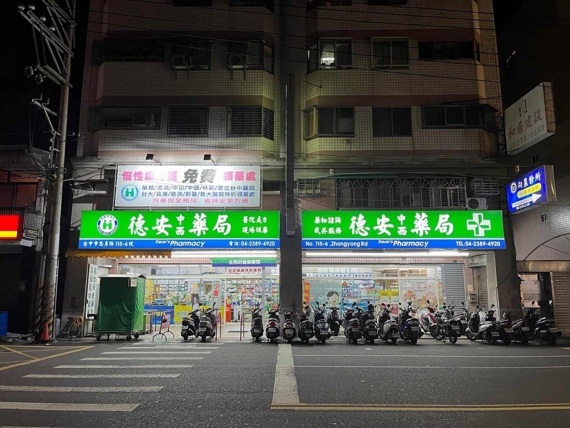 夜晚的德安藥局門市，綠色招牌寫著德安中西藥局、醫院處方現場領藥、藥物諮詢、戒菸服務